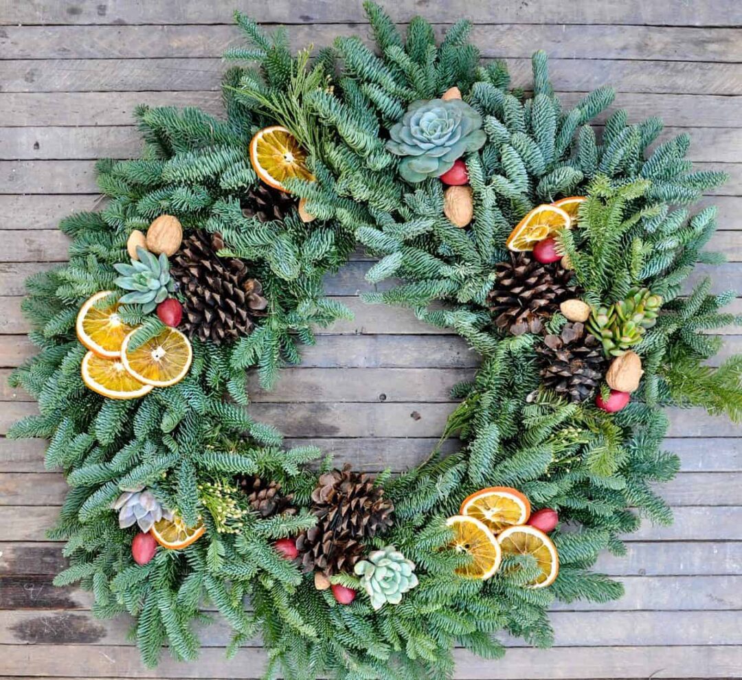Festive holiday wreath decorated with dried orange slices, pine cones, and berries.