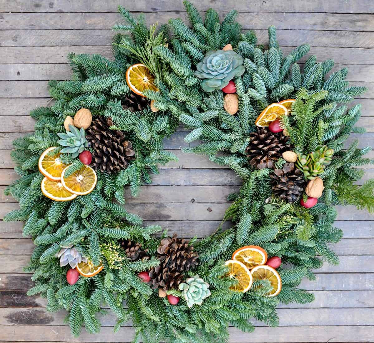 Festive holiday wreath decorated with dried orange slices, pine cones, and berries.